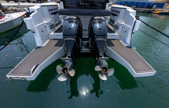 Fototapeta Close-up view of a luxury boat's twin outboard motors docked at marina. Clean, modern design with reflections on water and sunny weather.