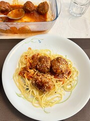 Homemade spaghetti with meatballs and tomato sauce served on a white plate