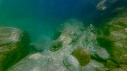 Rocky bottom of a freshwater river. View of large and small stones on the river bottom underwater.