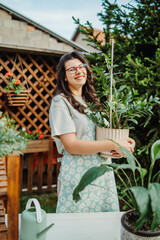 Young woman taking care of plants with water can and mister	

