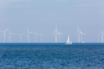 Wind turbines in the sea, Image shows a large number of wind turbines on a off shore wind farm off the coast of the Netherlands with a yacht passing by
