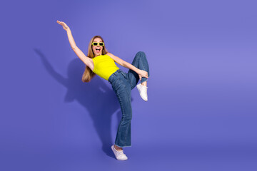Cheerful young woman in bright outfit posing joyfully against a vibrant purple background with...