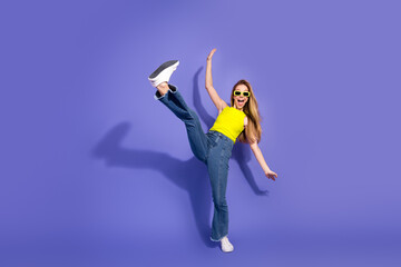Vibrant young woman in casual outfit striking a playful pose against a purple backdrop, expressing...