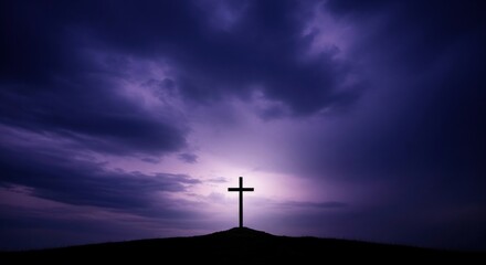 Naklejka premium Christian cross silhouette on hill against dramatic dark purple sky with light