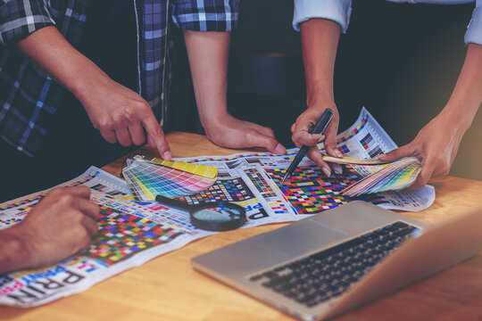 Team graphic designer checking print quality of media graphics proof print and color guides in printing industry. Selected focus