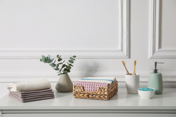Fototapeta premium Clean waffle towels and other bath products on white dresser in bathroom