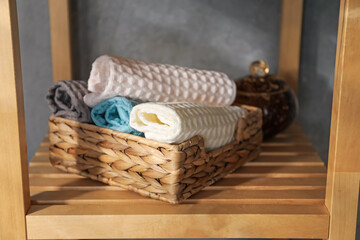 Fototapeta premium Clean waffle towels on wooden shelving unit near grey wall in bathroom, closeup