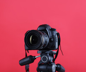Modern professional video camera on red background, closeup