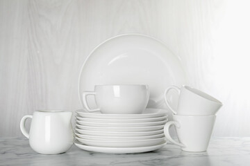 Different clean dishware on white marble table indoors