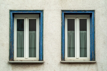 Hausfassade mit zwei, blau eingerahmten, Fenstern
