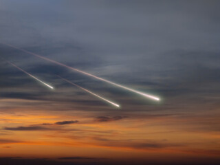 Meteors in the sky at sunset. Fireballs with trails above the clouds. Bright shooting stars...
