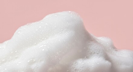 Fototapeta premium Close-up of rich, fluffy white soap foam against a soft pink background