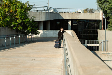 Young woman walking uphill on concrete path with suitcase