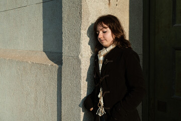 Woman with serious look leaning on concrete wall