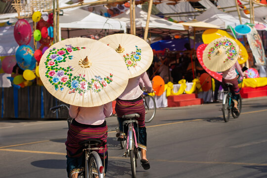 Women holding beautiful umbrellas and cycling. show at Bosang umbrella festival Chiang Mai, Thailand1