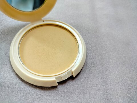 cosmetic packing compact powder with glass on grey background