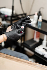 Gloved Hand Holding Small Dark Bottle with White Label
