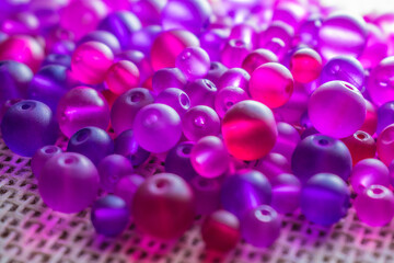 A colorful cascade of translucent purple and pink beads, catching the light on a textured surface, ready for your next creative endeavor. Great for DIY content ,ewelry, or abstract backgrounds