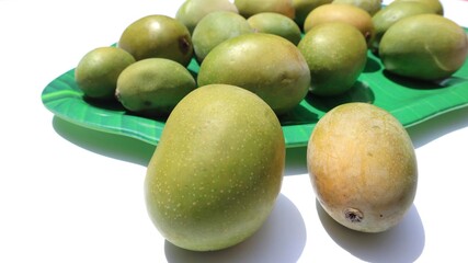 Tasty small sized desi mangos . Small mangos but are fully ripe, fibrous, juicy in tray on white...
