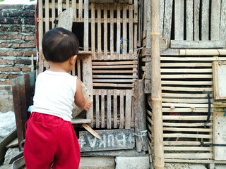 A little boy in red pants was in front of the chicken coop