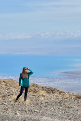 Female tourist looks into the distance. Young woman admires the views of nature. Mountains and Lake...