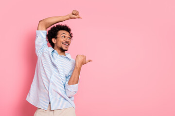Young man in casual shirt posing with cheerful gestures against pink background illustrating joyful...
