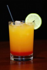 Tequila Sunrise Cocktail: A refreshing Tequila Sunrise cocktail in a rocks glass, garnished with a lime wedge. The vibrant layers of orange and red create a visually appealing drink.