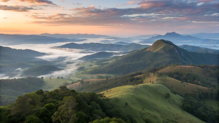 Aerial view of forested mountain peaks emerging from a thick sea of clouds at sunrise. The soft mist flows between the hills, creating a surreal, dreamlike atmosphere with warm light on the horizon. P