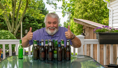 An Older Beer Loving Man Enjoying a Cheerful Moment With Full Beer Bottles on a Sunny Deck
