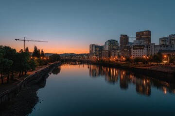 City skyline reflected in river at dusk with construction crane in the distance