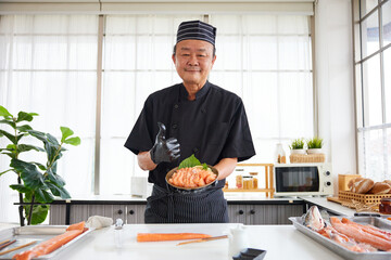 chef holding salmon sushi and thumbs up pose in the kitchen