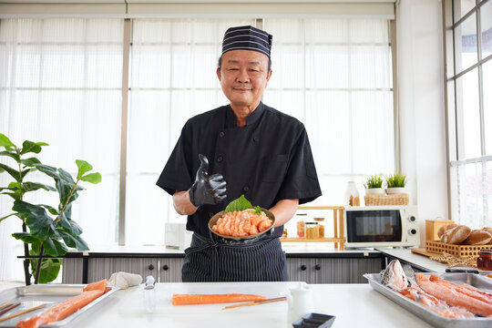 chef holding salmon sushi and thumbs up pose in the kitchen