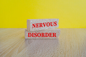 Brick blocks with concept word NERVOUS Disorder on brick blocks. Beautiful wooden table yellow...