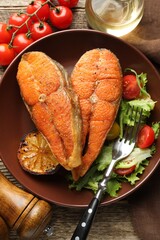 Seafood. Tasty salmon steaks served with salad and lemon on wooden table, flat lay