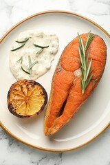 Seafood. Tasty salmon steak served with sauce, rosemary and lemon on white marble table, top view