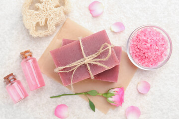 Soap bars, sea salt, essential oils and beautiful roses on beige table, flat lay