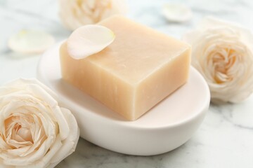 Soap bar and flowers on white marble table, closeup