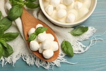 Mozzarella cheese balls and basil on blue wooden table, flat lay