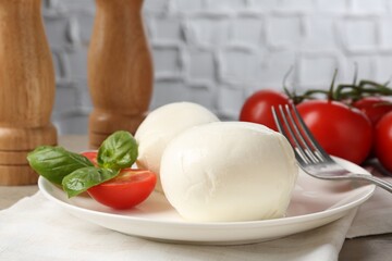 Tasty mozzarella cheese balls, tomatoes and basil on table, closeup