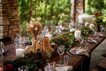 Banquet decoration in a simple rustic style with grass, greenery, simple objects and fabrics. Wedding table setting for guests
