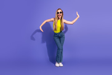 Brightly styled young woman posing energetically in casual fashion on a vibrant purple background...