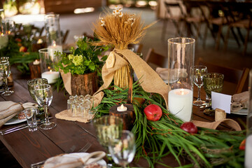 Banquet decoration in a simple rustic style with grass, greenery, simple objects and fabrics. Wedding table setting for guests