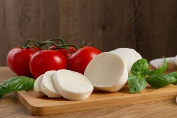 Tasty mozzarella, tomatoes and basil on wooden table, closeup