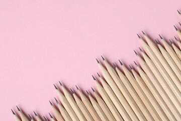 Many graphite pencils on pink background, flat lay. Space for text