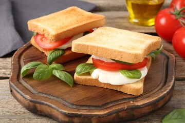 Tasty sandwiches with mozzarella cheese, tomatoes and basil on wooden table, closeup