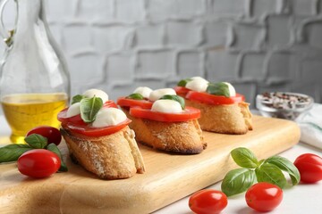 Tasty sandwiches with mozzarella cheese, tomatoes and basil on white table, closeup