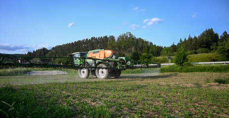 Tractor spraying pesticides on crops in cultivated field, ensuring healthy growth and protecting against pests