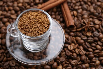 Cup with granulated instant coffee and cinnamon on beans, closeup. Space for text