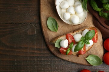 Tasty sandwich with mozzarella cheese, tomatoes and basil on wooden table, flat lay. Space for text