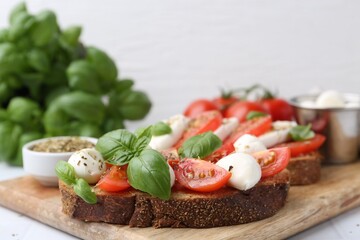 Tasty sandwiches with mozzarella cheese, tomatoes, basil and spices on light table, closeup